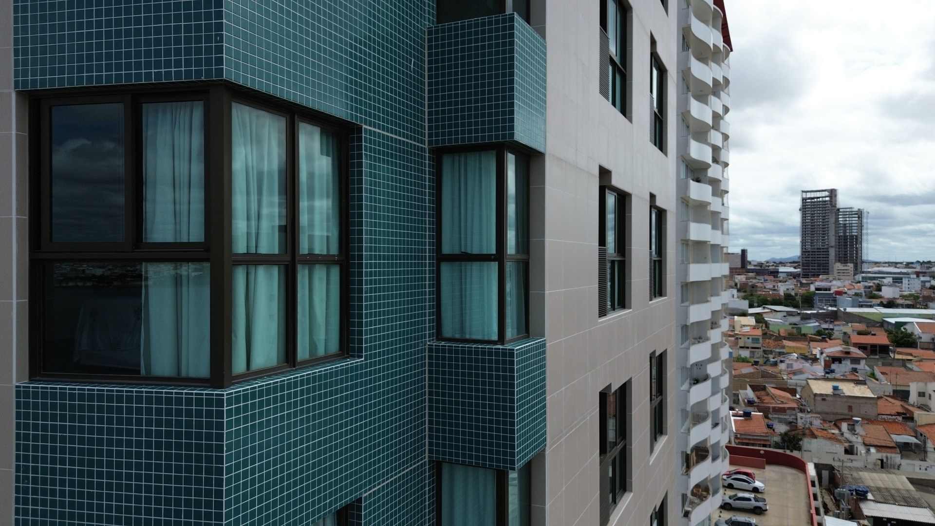 Fachada do prédio vista do drone, do alto, com a cidade ao fundo.