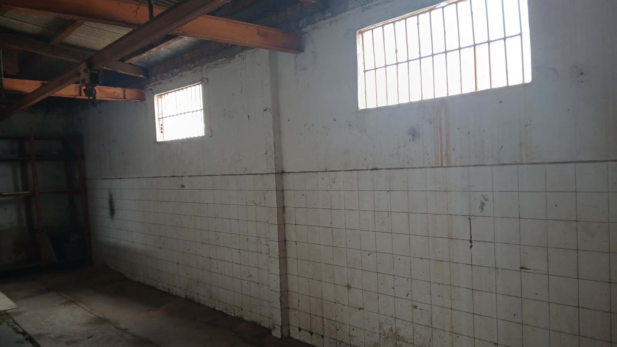 Parede do depósito com azulejos manchados e pintura desgastada.