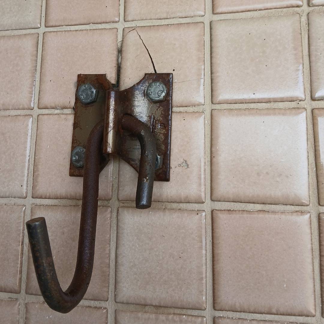 Entrada: gancho de metal preso na parede de azulejos da sacada, fotografado do mesmo ponto.