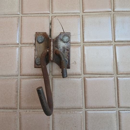 Saída: gancho de metal preso na parede de azulejos da sacada, fotografado do mesmo ponto.