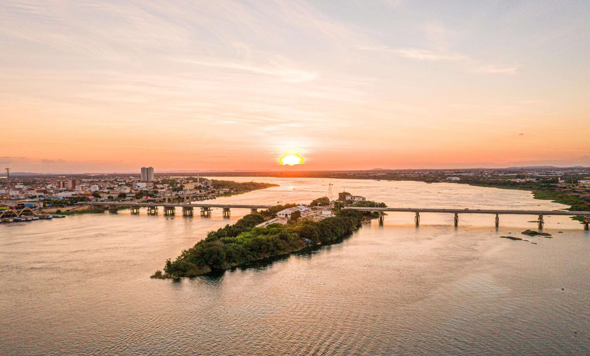 Vista aérea do rio São Francisco ao entardecer, com a ponte ligando Petrolina e Juazeiro.
