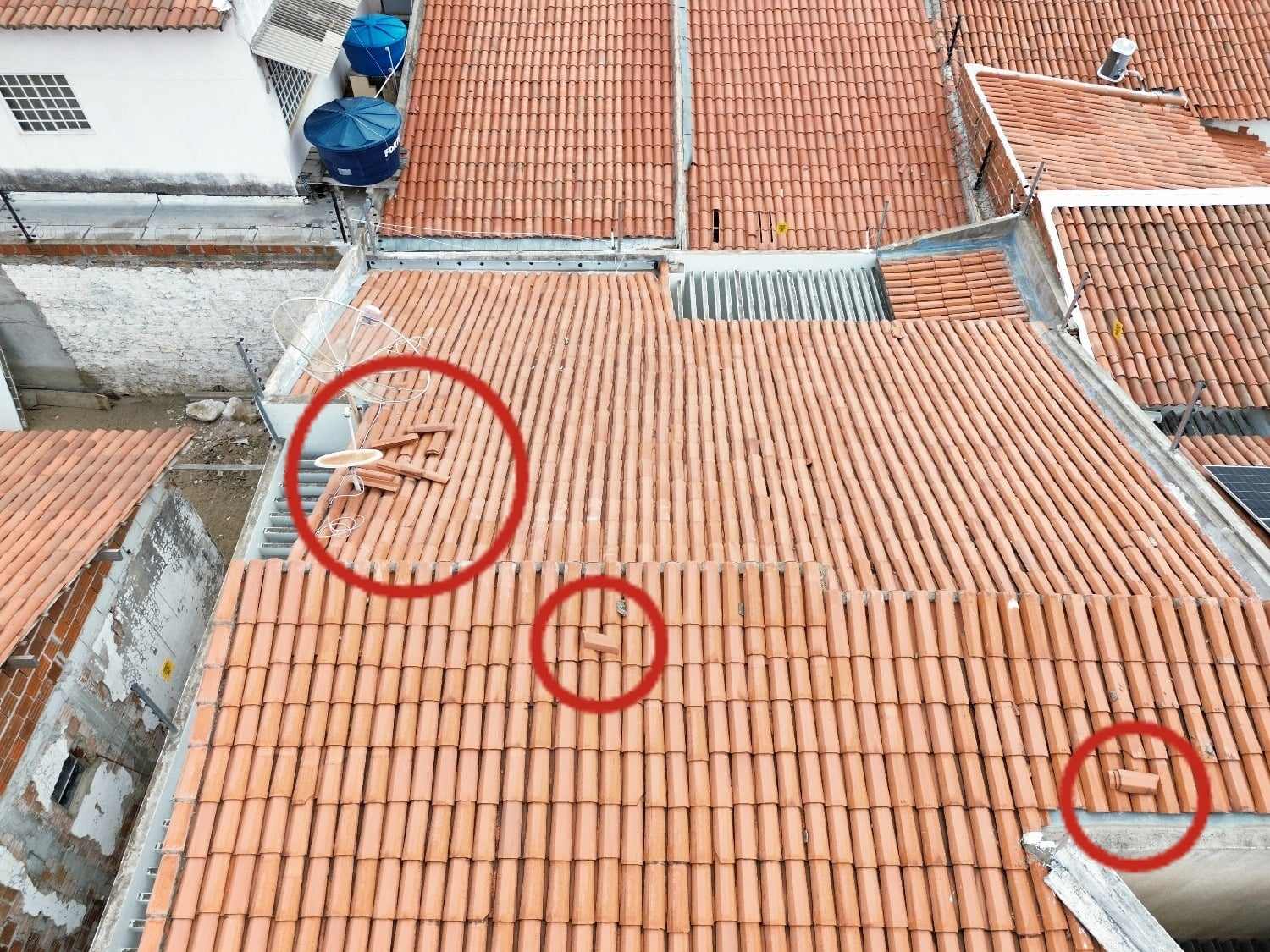 Foto de drone de telhado cerâmico com três pontos de telhas deslocadas marcados em círculos.
